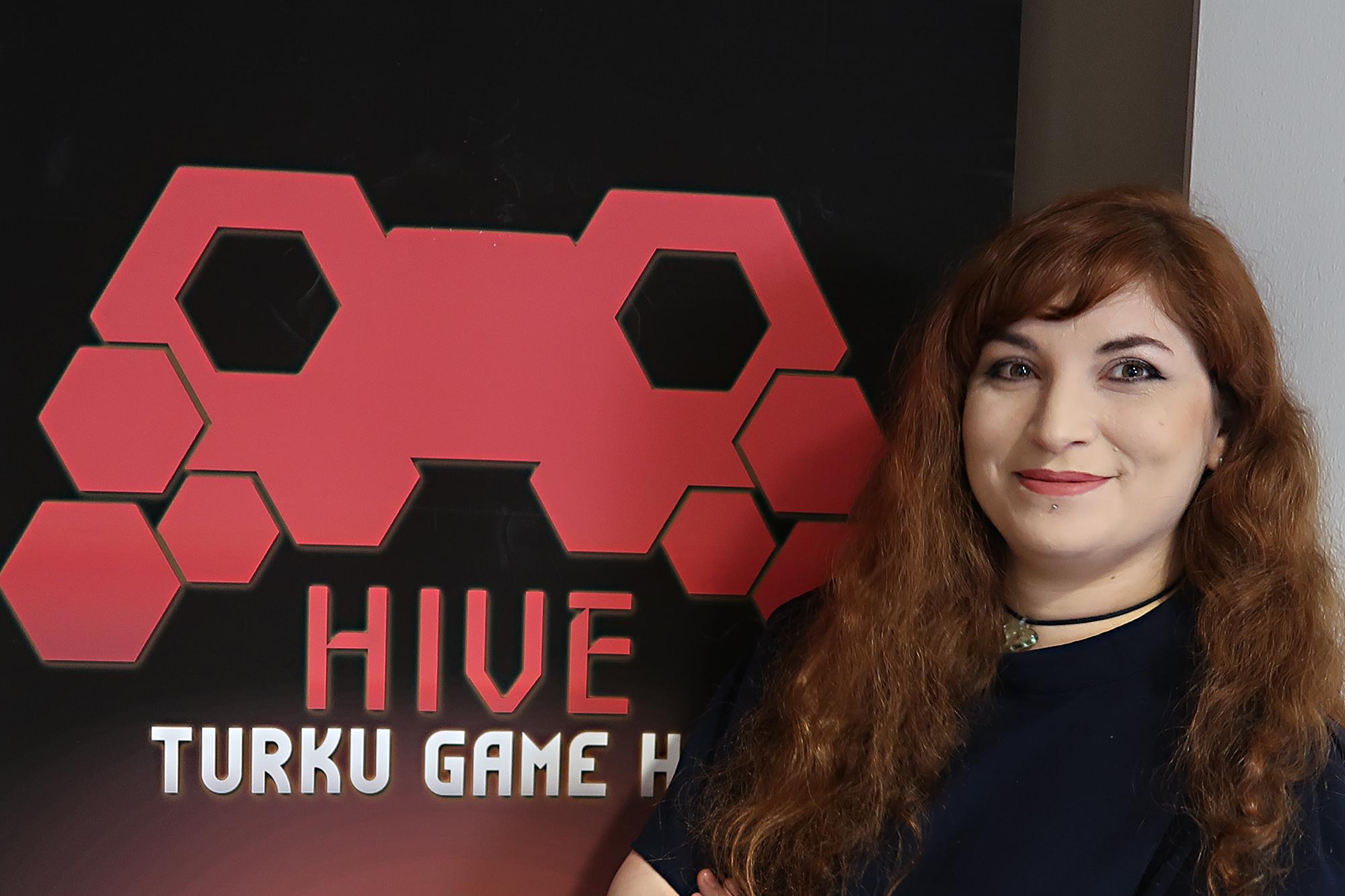 Ruskeatukkainen nainen Hive Turku Game Labin logon vieressä.