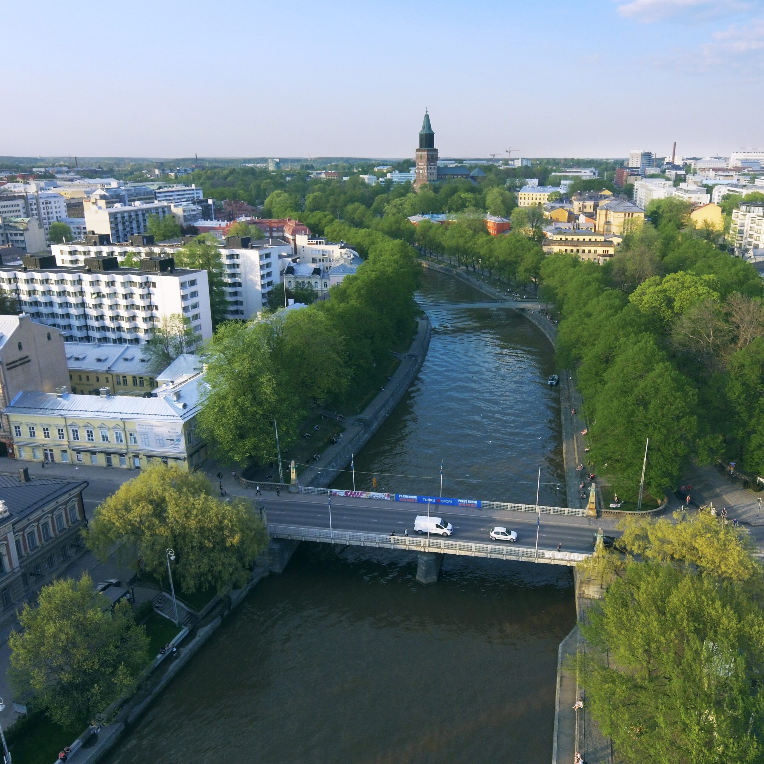 Ilmakuva Turun kaupungista. Kuvassa keskellä Aurajoki, taustalla vehreää kaupunkimaisemaa ja Turun Tuomiokirkko.